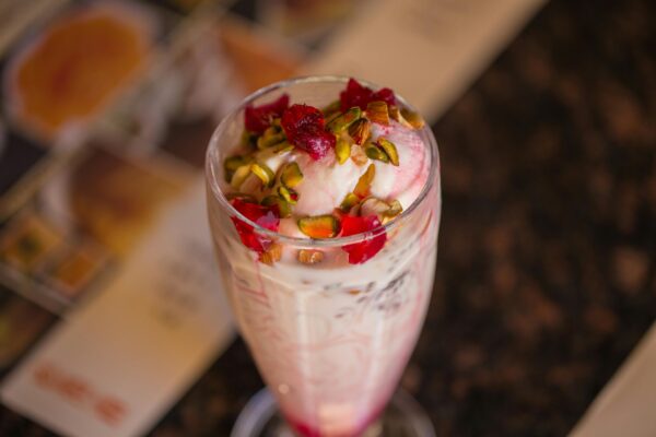 A tempting glass of falooda topped with pistachios and rose syrup, captured elegantly in Dubai.