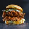 Delicious fried chicken burger topped with pickles and creamy cheese sauce.